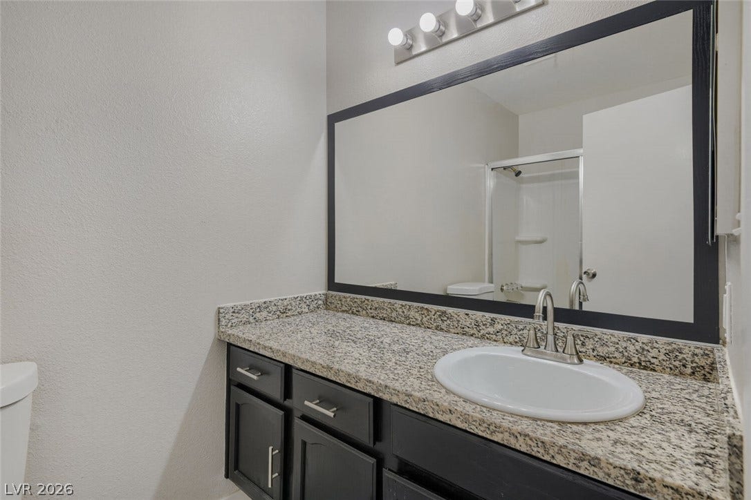 2343 Valleywood Road, Henderson, NV 89014 A sleek vanity with granite counters and a large mirror defines this functional bathroom.