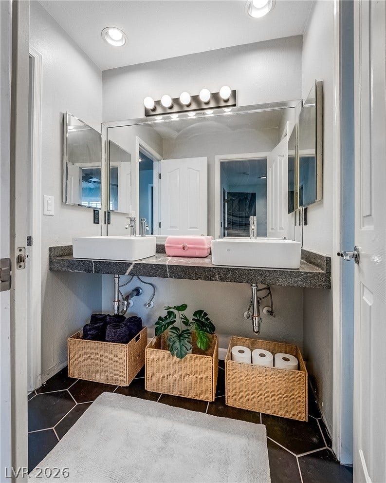 2393 Stansbury Court, Henderson, NV 89052 Double vanities with stylish vessel sinks complement the tiled floor in this bright bathroom.