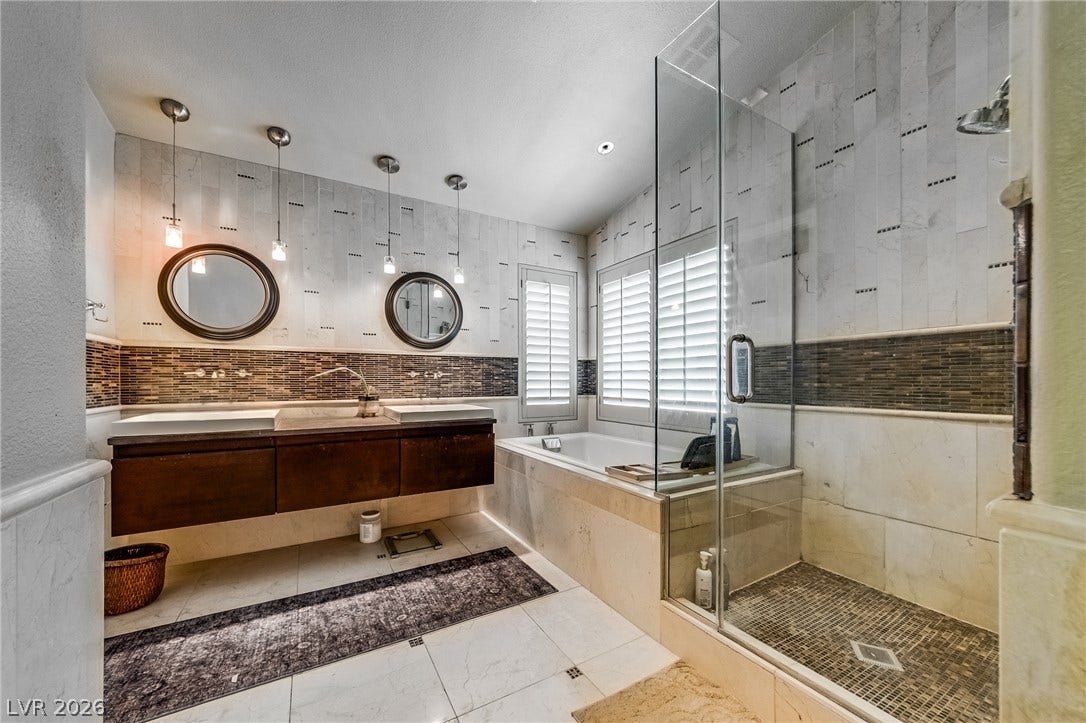 2393 Stansbury Court, Henderson, NV 89052 Luxurious primary bathroom featuring a dual vanity, an integrated tub, and a spacious glass-enclosed shower.