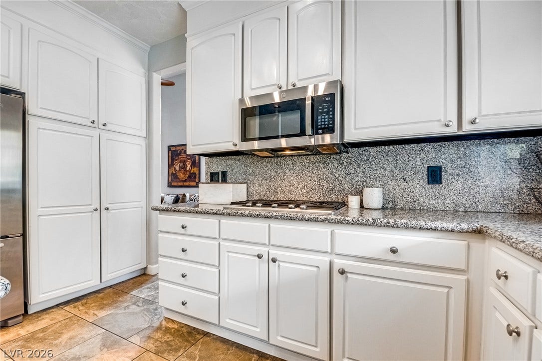 2393 Stansbury Court, Henderson, NV 89052 White cabinetry with sleek hardware and granite countertops complete this inviting kitchen.