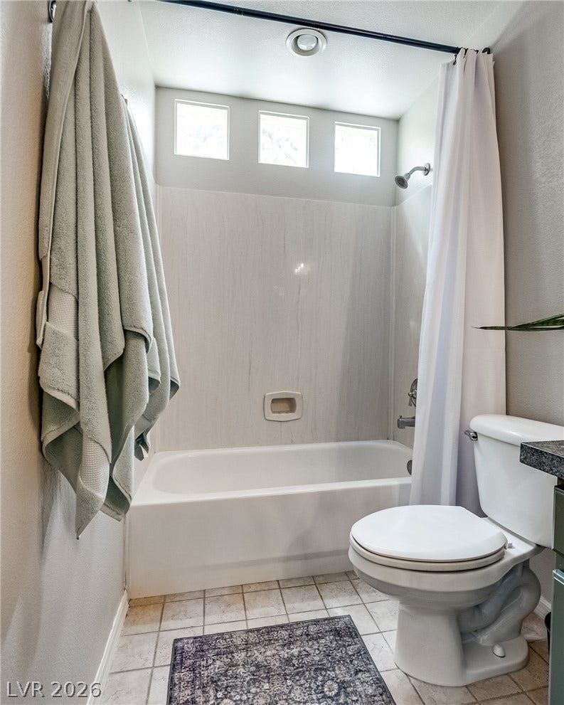 2393 Stansbury Court, Henderson, NV 89052 Well-lit bathroom features a full bathtub with an overhead shower and tile flooring.