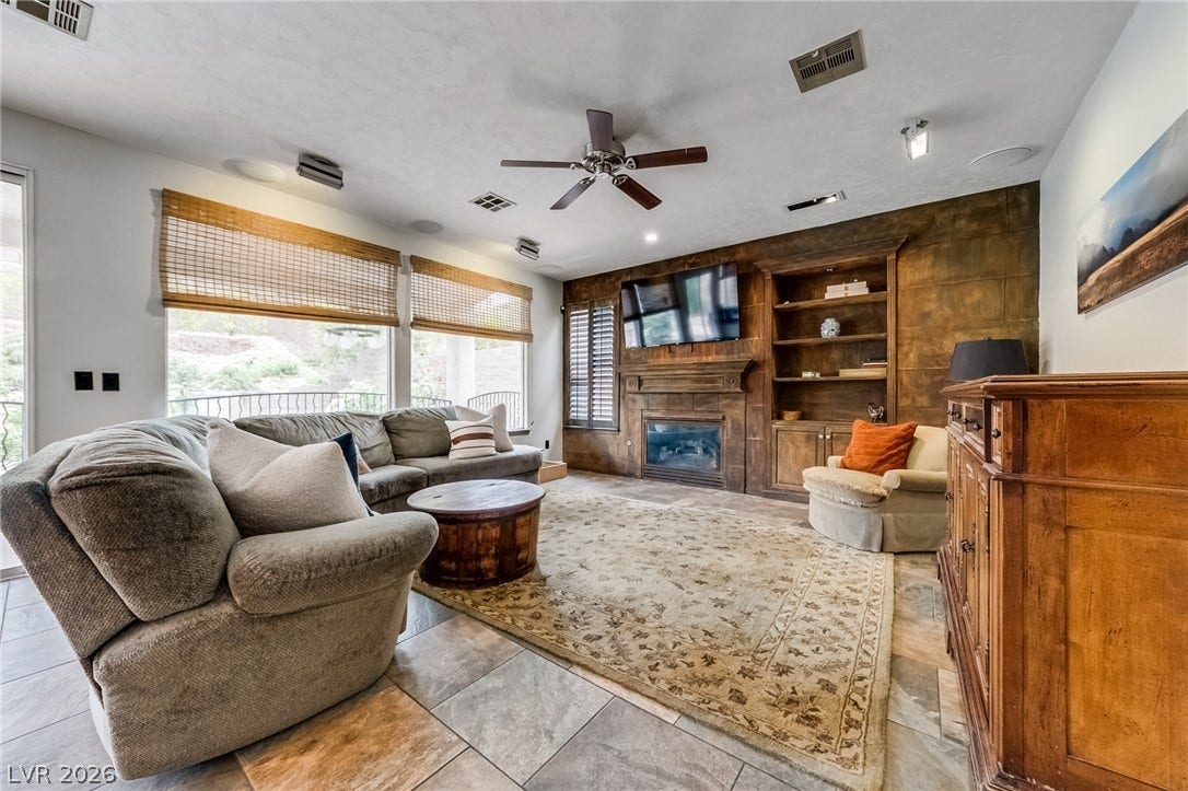 2393 Stansbury Court, Henderson, NV 89052 A refined living space with built-in features, a fireplace, and elegant tile flooring offers comfort and style.