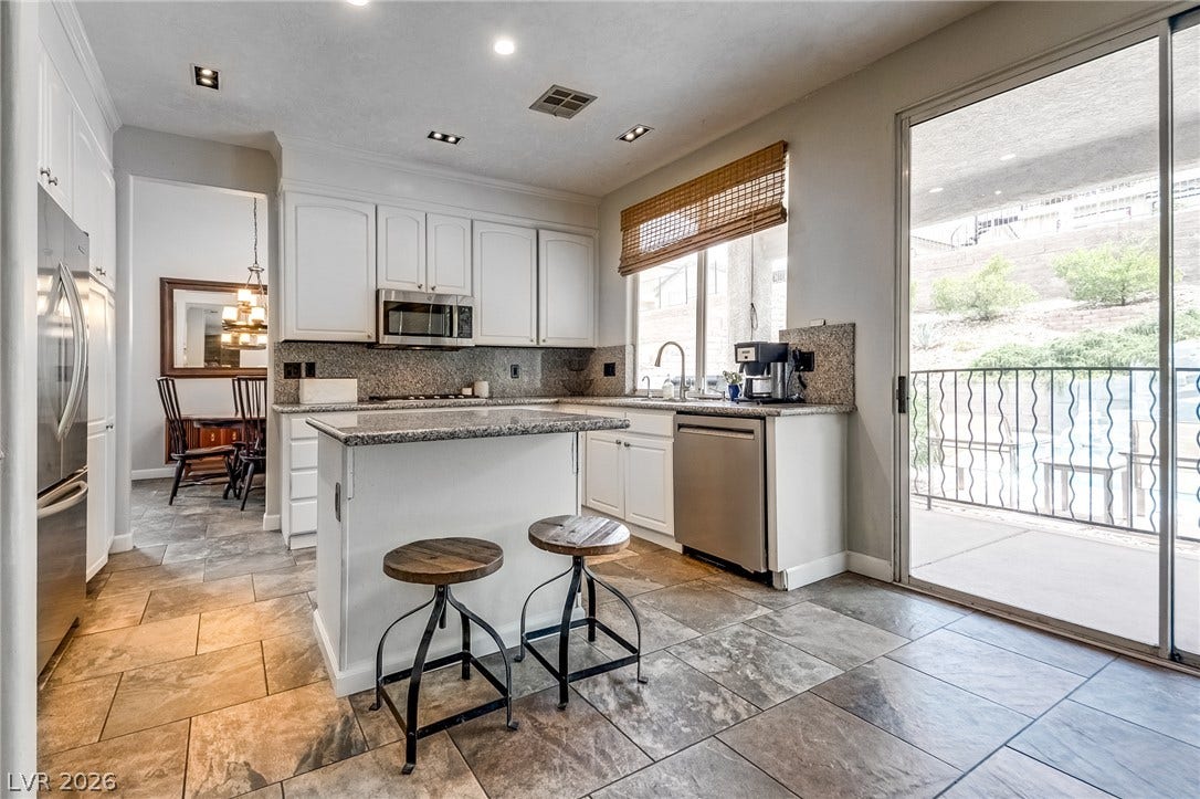 2393 Stansbury Court, Henderson, NV 89052 A well-appointed kitchen features a practical island, ample counter space, and convenient balcony access.