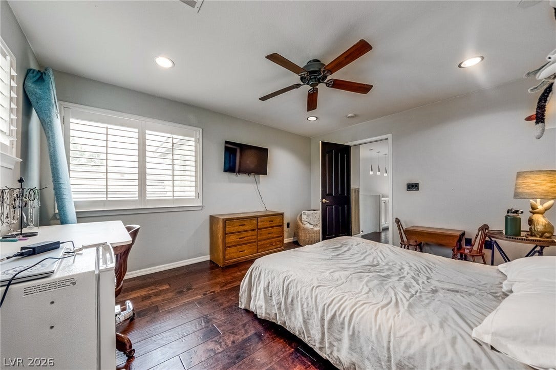 2393 Stansbury Court, Henderson, NV 89052 Rich hardwood floors complement this cozy bedroom with a ceiling fan and natural light.