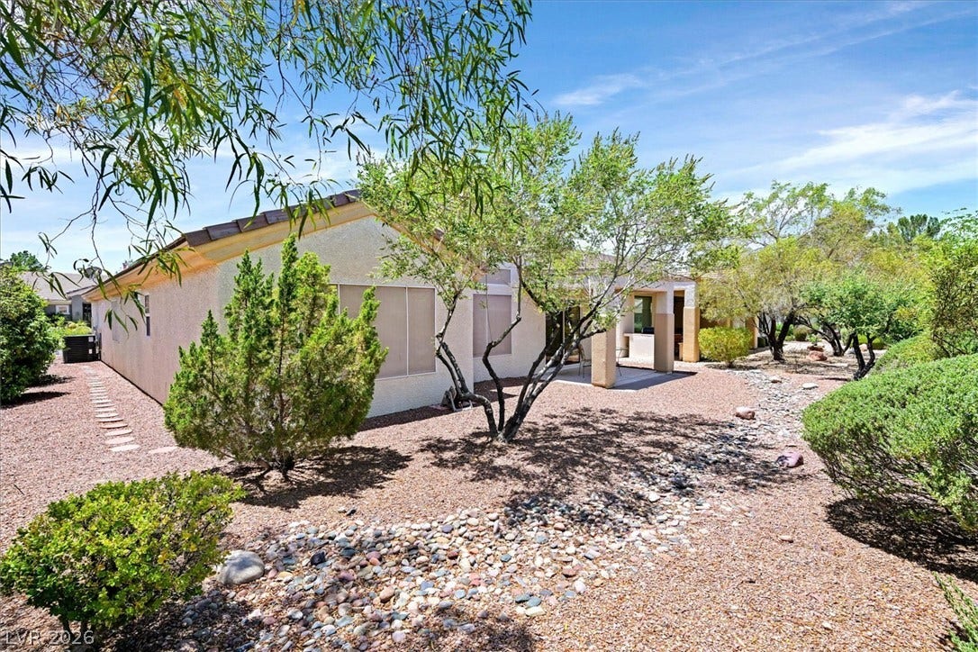 468 Bonnie Brook Place, Henderson, NV 89012 Mature trees frame a sun-drenched exterior, showcasing a charming outdoor patio.