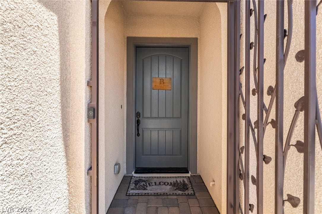 330 Meadow Brush Place, Henderson, NV 89011 An inviting entry showcases a dark wood door behind an ornamental wrought iron security gate.
