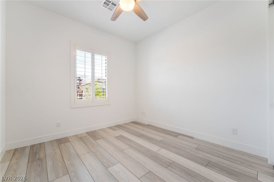 330 Meadow Brush Place, Henderson, NV 89011 An airy bedroom with wide plank flooring and a classic window with louvered shutters.