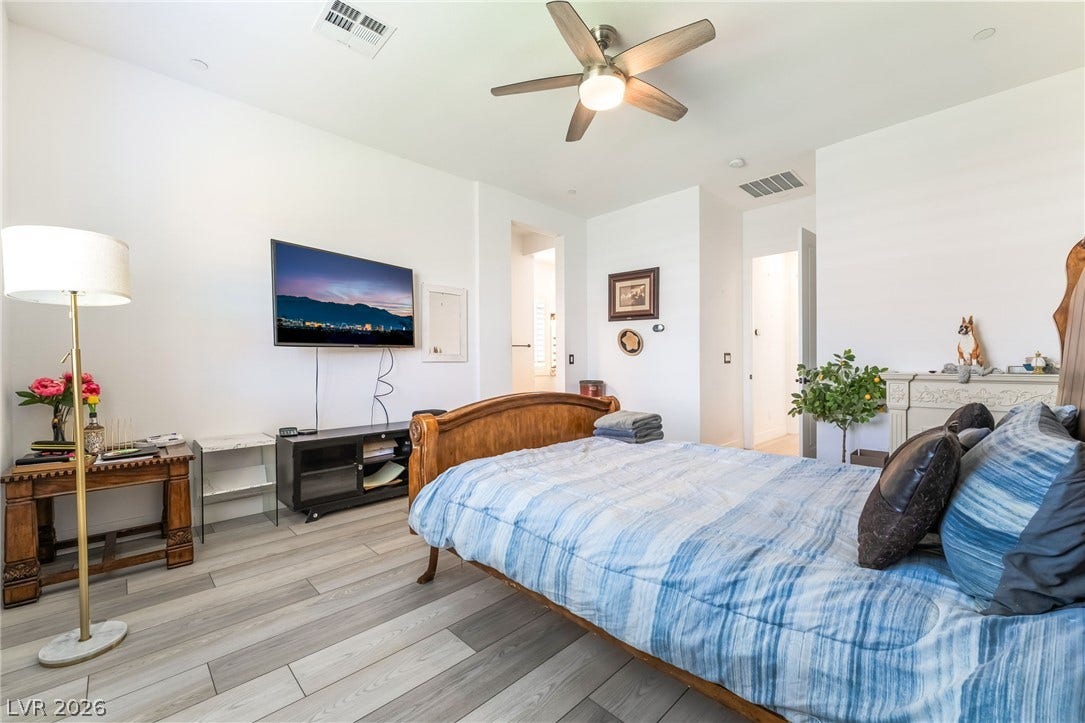 330 Meadow Brush Place, Henderson, NV 89011 Relax in a bedroom with natural light and refined plank flooring, perfect for peaceful nights.