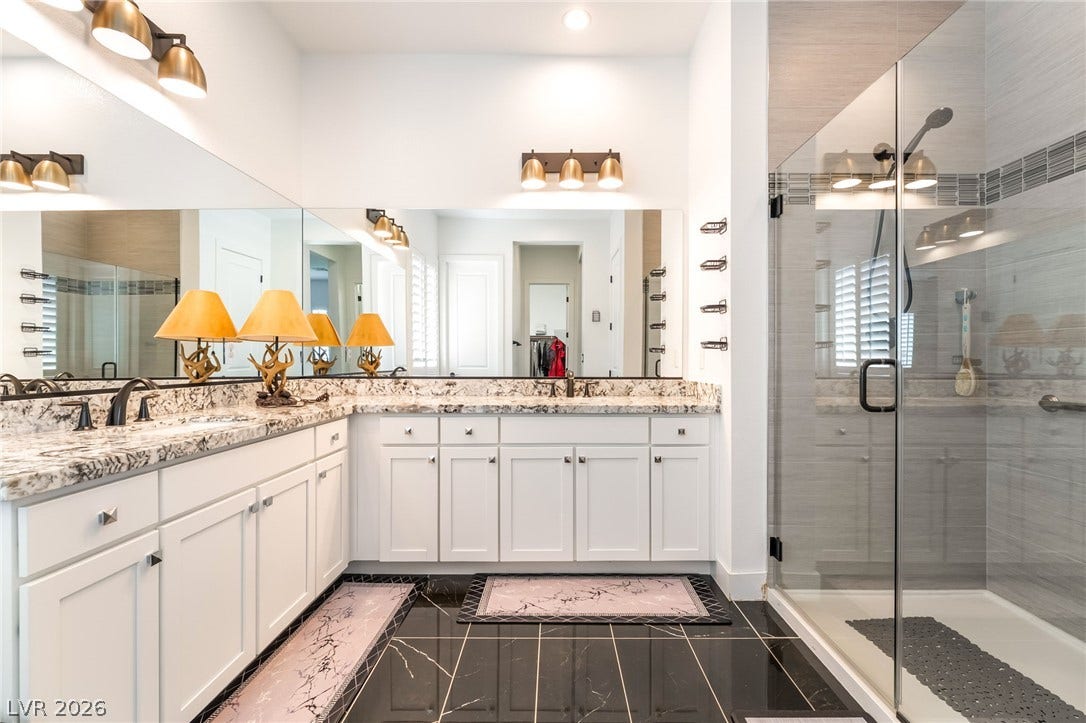 330 Meadow Brush Place, Henderson, NV 89011 Dual vanities with stone counters and an enclosed glass shower highlight this contemporary bathroom.