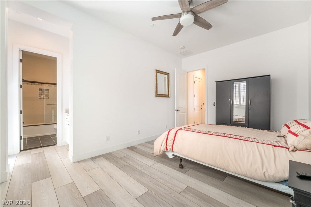 330 Meadow Brush Place, Henderson, NV 89011 Light-toned flooring extends into a well-lit bedroom featuring a sleek ceiling fan and an adjacent private bathroom.