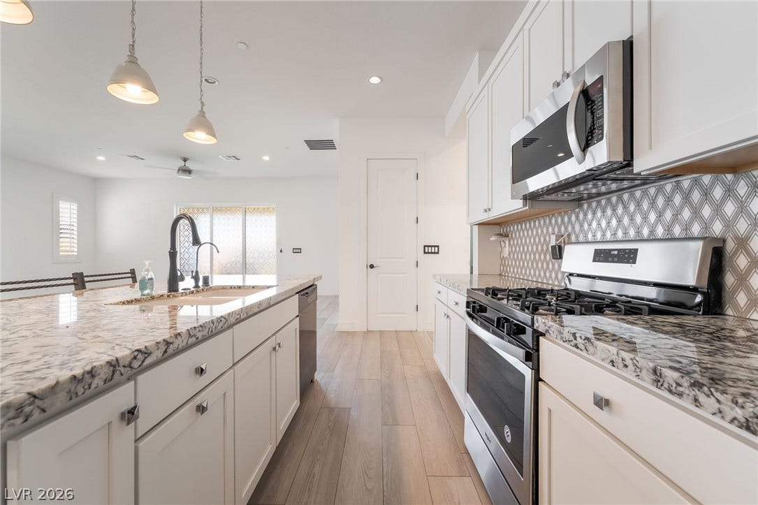 330 Meadow Brush Place, Henderson, NV 89011 A well-lit kitchen featuring stone counters and wood flooring, perfect for culinary endeavors.
