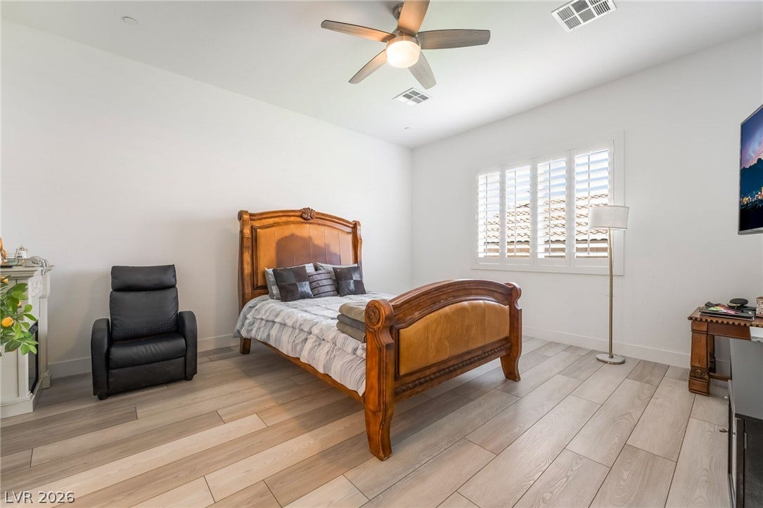 330 Meadow Brush Place, Henderson, NV 89011 A quiet bedroom offering comfort and privacy with light wood flooring and a refreshing ceiling fan.