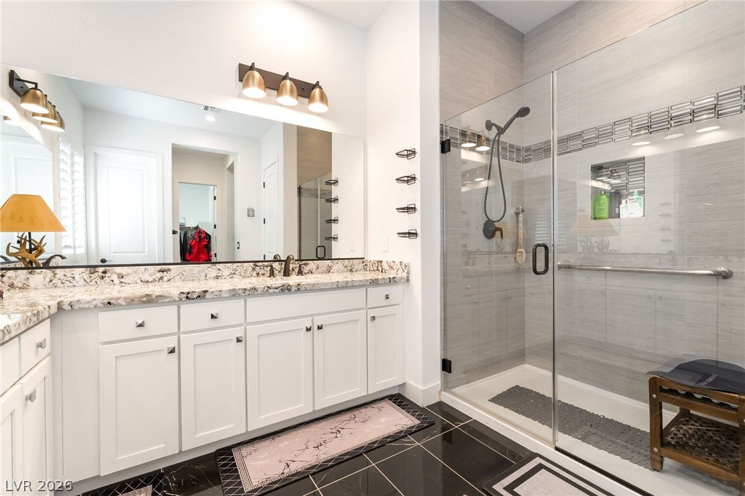 330 Meadow Brush Place, Henderson, NV 89011 A well-appointed primary bathroom features a double vanity and a glass-enclosed shower with tile surround.