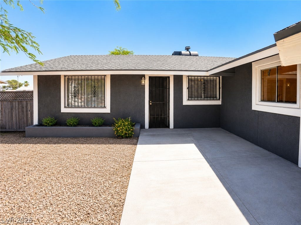 Well-maintained dark exterior with a stone bed and a smooth concrete path leading to the entrance.