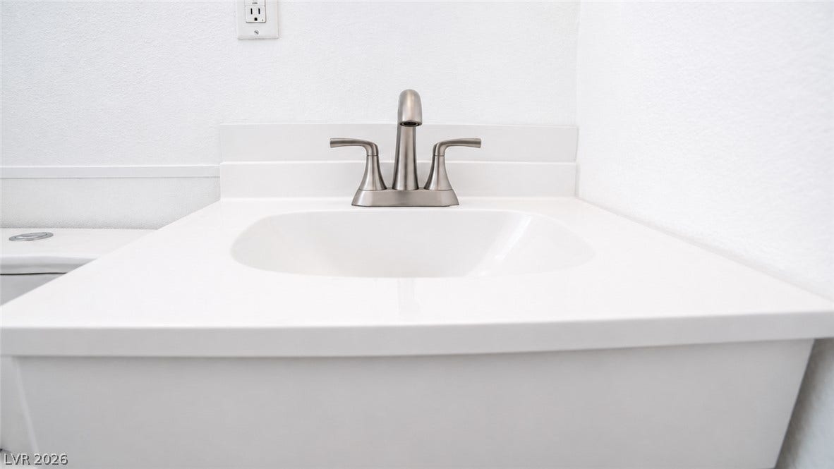 A pristine white vanity with a brushed nickel faucet adds a touch of modern simplicity to the space.