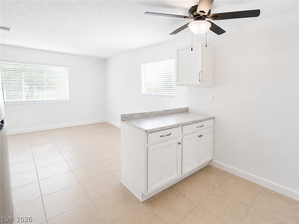 A well-lit, open-concept area featuring ample cabinet space and ceramic tile flooring.