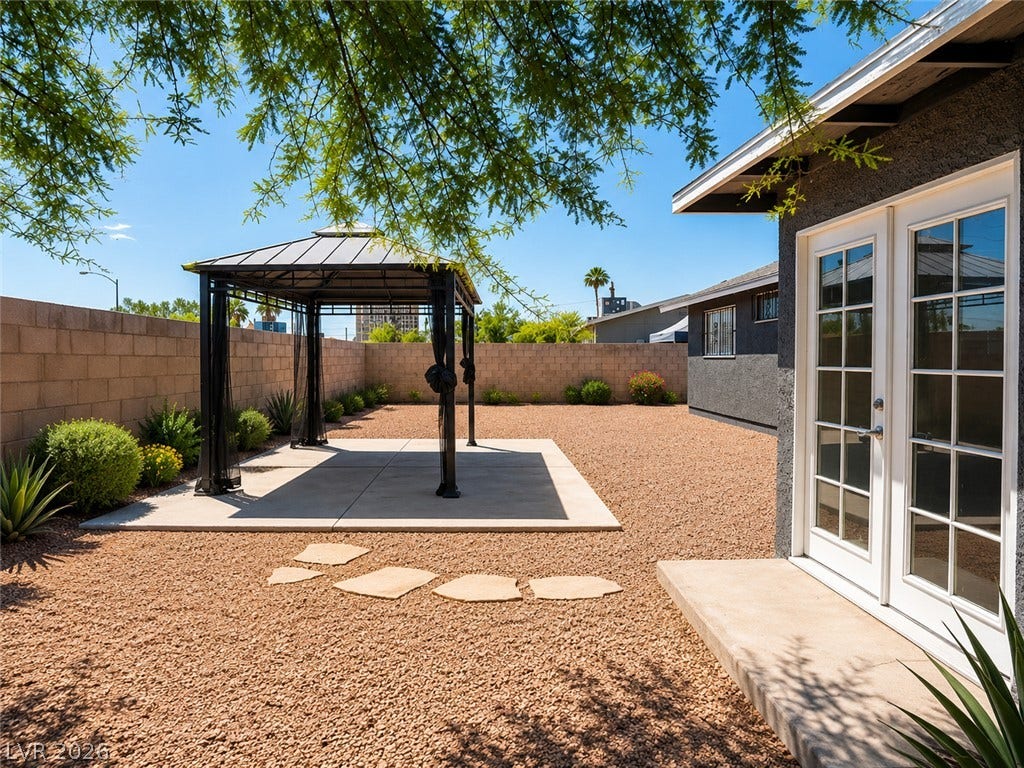A spacious, gravel-covered yard features a private gazebo, perfect for outdoor relaxation.