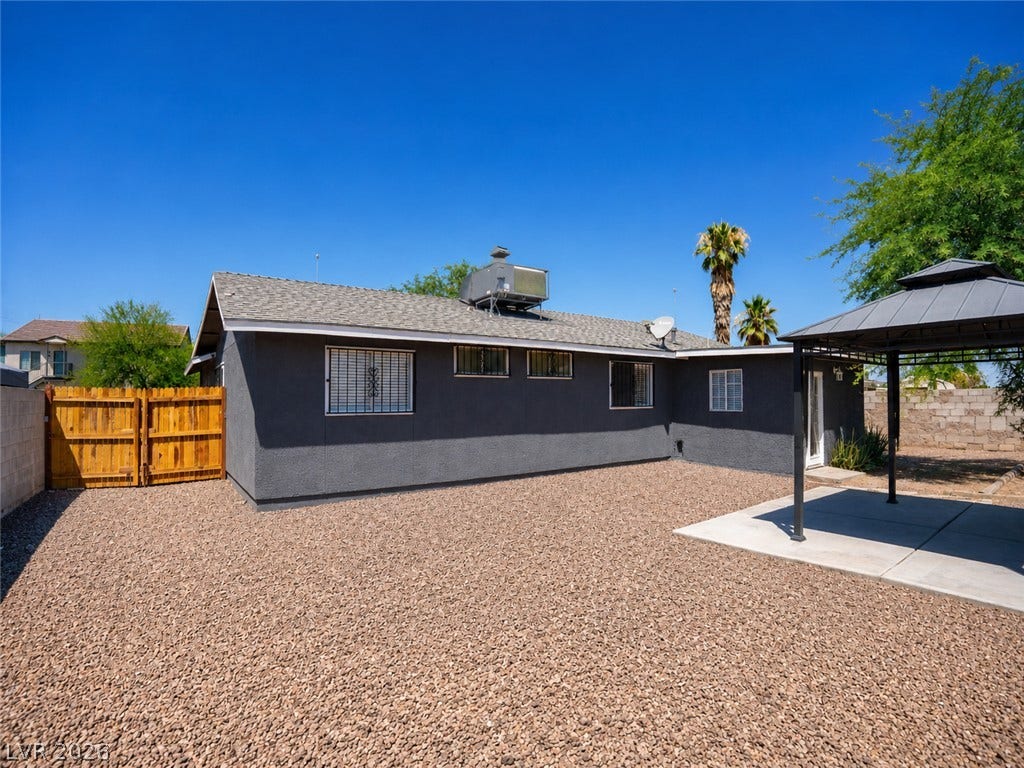 An inviting backyard oasis offers a gravel expanse, covered patio, and a secure wooden fence.