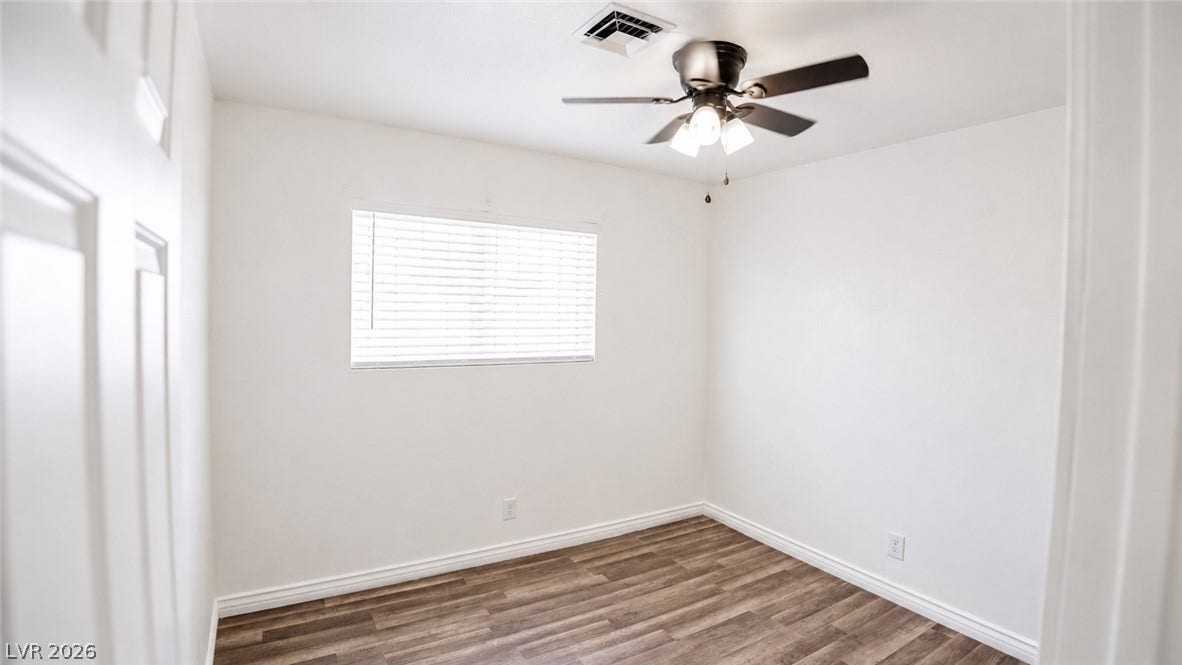 A well-lit bedroom features durable hardwood flooring and a ceiling fan for comfort.
