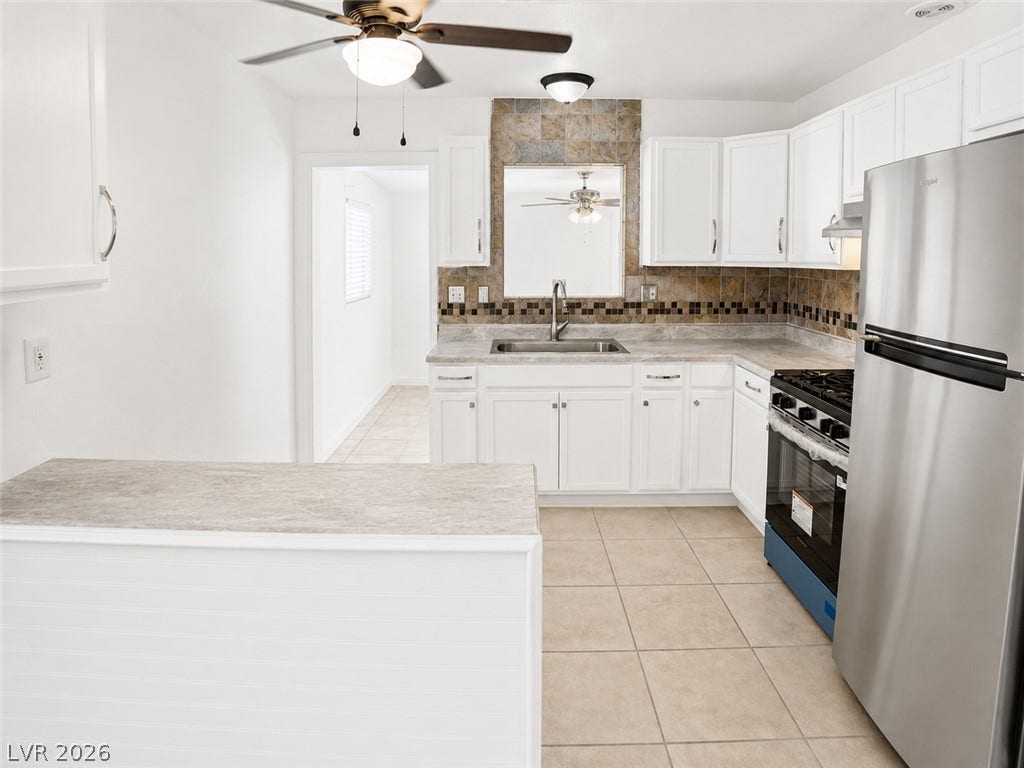 A well-lit kitchen with sleek white cabinetry and modern stainless steel appliances.