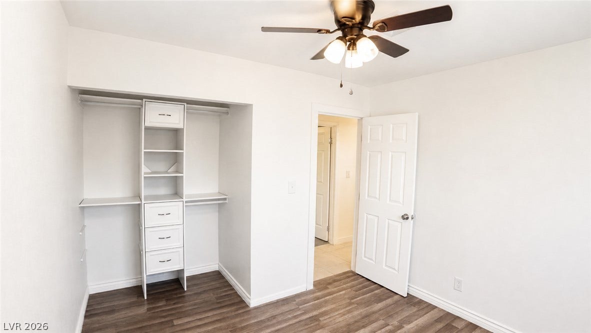 Custom closet organizers complement the rich wood flooring in this well-appointed bedroom.