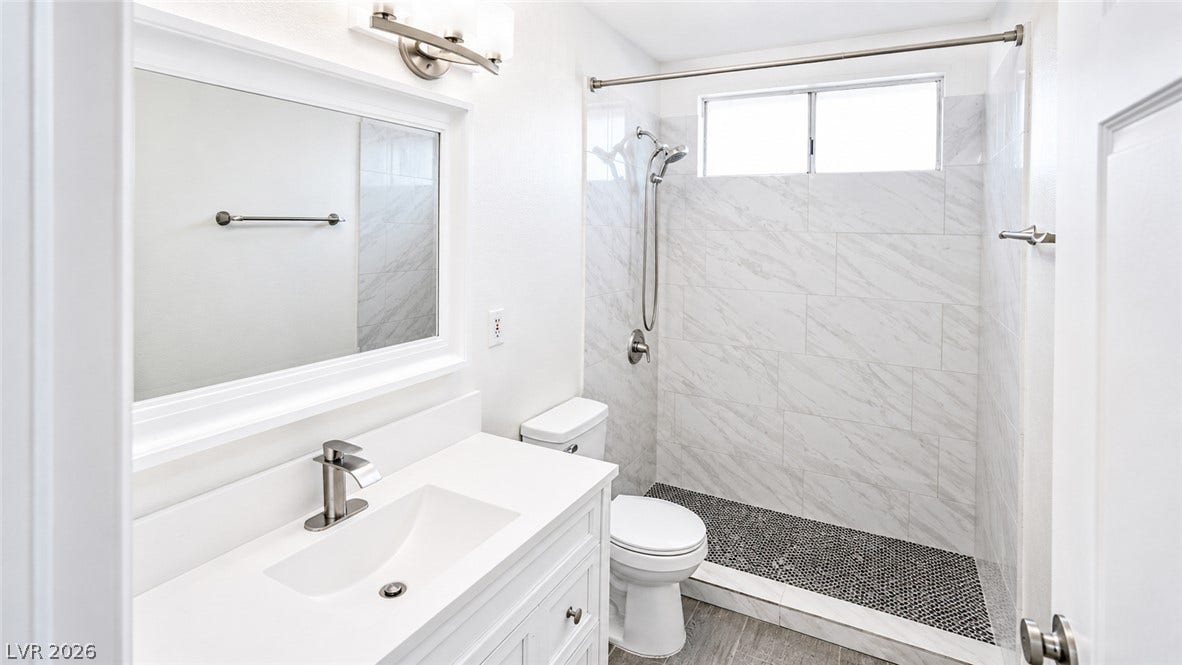 White vanity with a large mirror and sleek fixtures create a clean, minimalist bathroom.