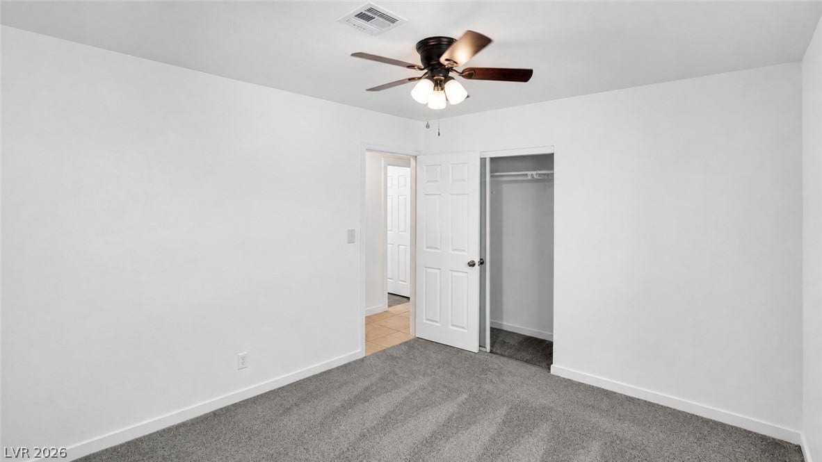 A well-proportioned bedroom offers comfort with plush carpeting and a modern ceiling fan.