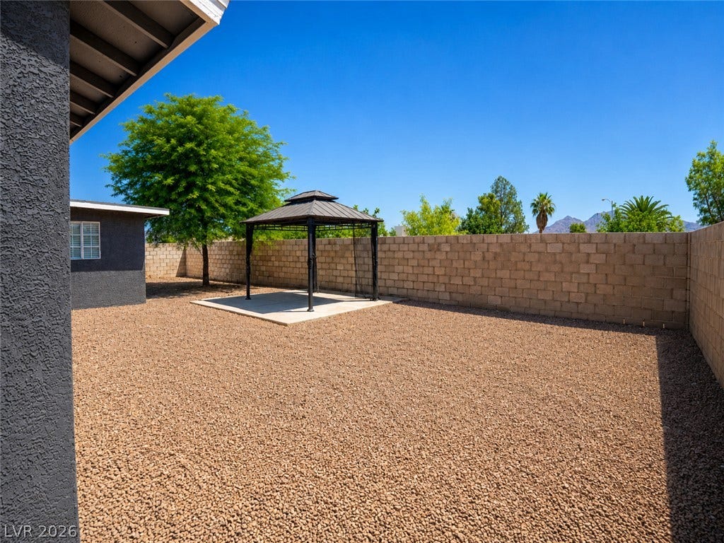 A spacious yard features a gazebo, ideal for outdoor entertaining under the clear sky.