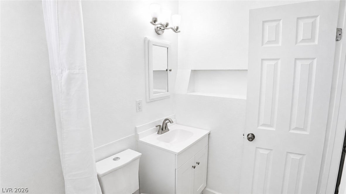 A pristine bathroom features a classic vanity and contemporary fixtures, presenting a fresh appeal.