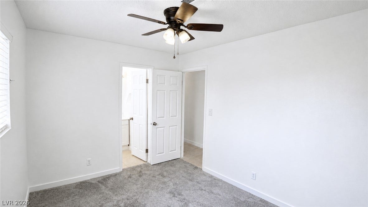 A well-lit bedroom features plush carpeting and a convenient ceiling fan.