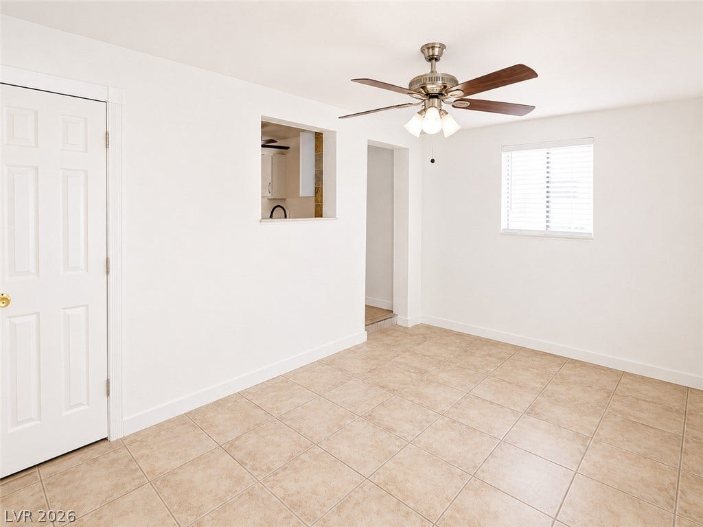 A living space offers a pass-through window to the kitchen and an inviting ceiling fan for comfort.
