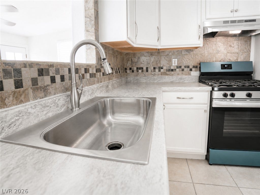 Well-lit kitchen with sleek countertops, modern tile backsplash, and essential cooking appliances.