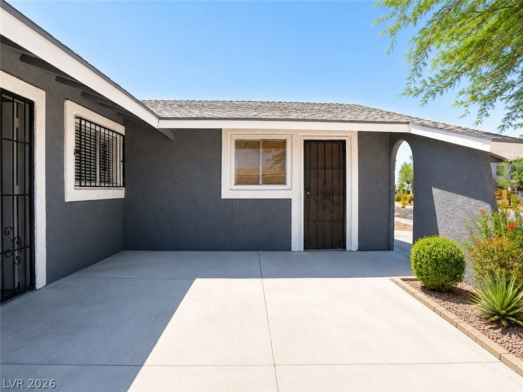 A welcoming entry area with clean concrete leads to a home featuring stucco siding.