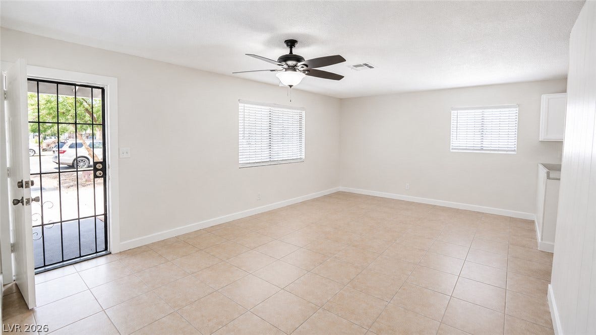 A spacious, naturally illuminated room featuring durable tiled flooring and a convenient ceiling fan.