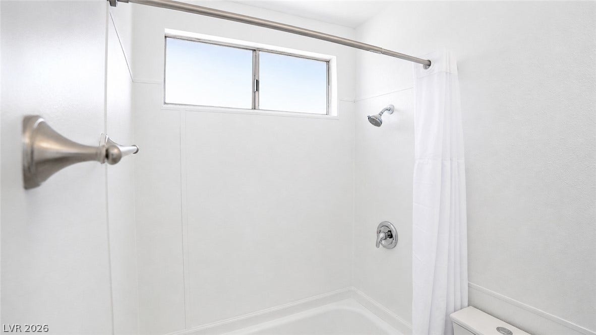 A well-appointed bathroom features a bathtub with an overhead window, offering natural illumination.