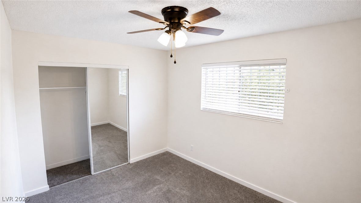 A well-lit bedroom provides comfort and style, with plush carpet and a convenient closet.