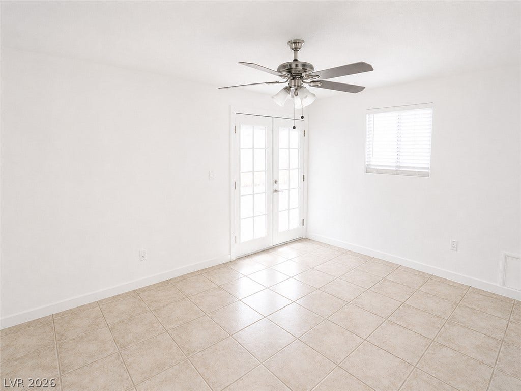 Natural light pours into this room, illuminating the pristine tile flooring and French doors.