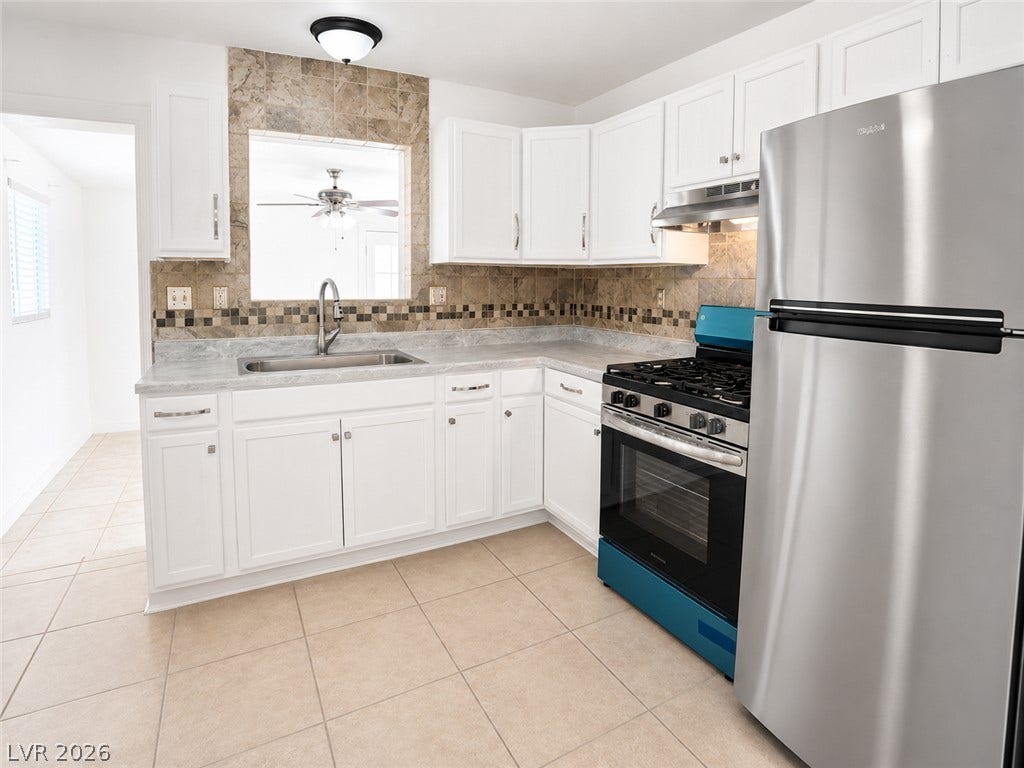 A well-equipped culinary space offers white cabinetry, tile flooring, and essential stainless steel appliances.