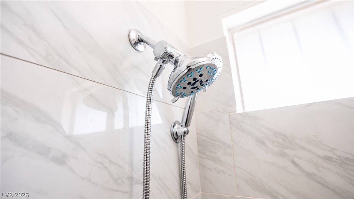 Marble-patterned tiled shower with a dual head system.