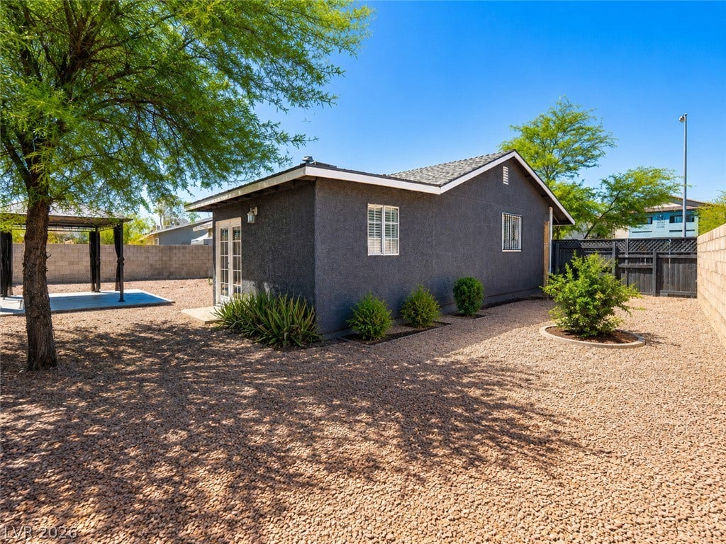 An inviting backyard oasis offers a shaded patio with a gazebo, perfect for relaxation.