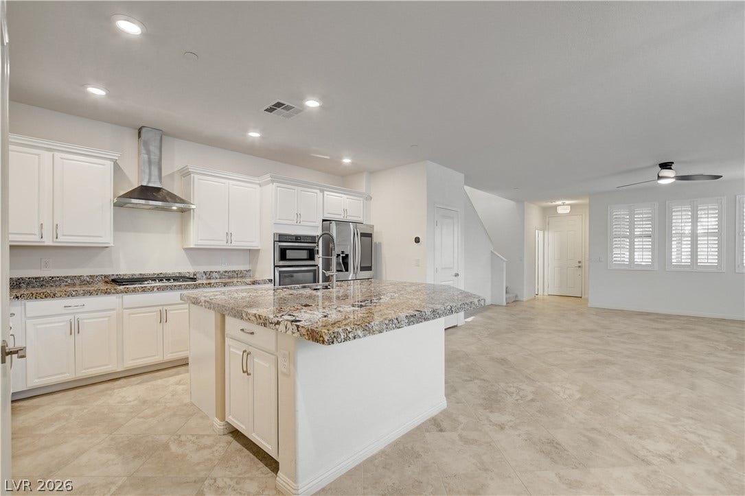 A gourmet kitchen boasts granite counters, stainless steel appliances, and an inviting island, flowing seamlessly into the adjacent living space.