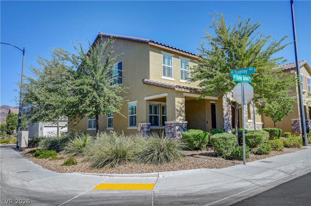 A corner lot residence boasts desert-friendly landscaping with mature trees and a sturdy stucco and stone facade.