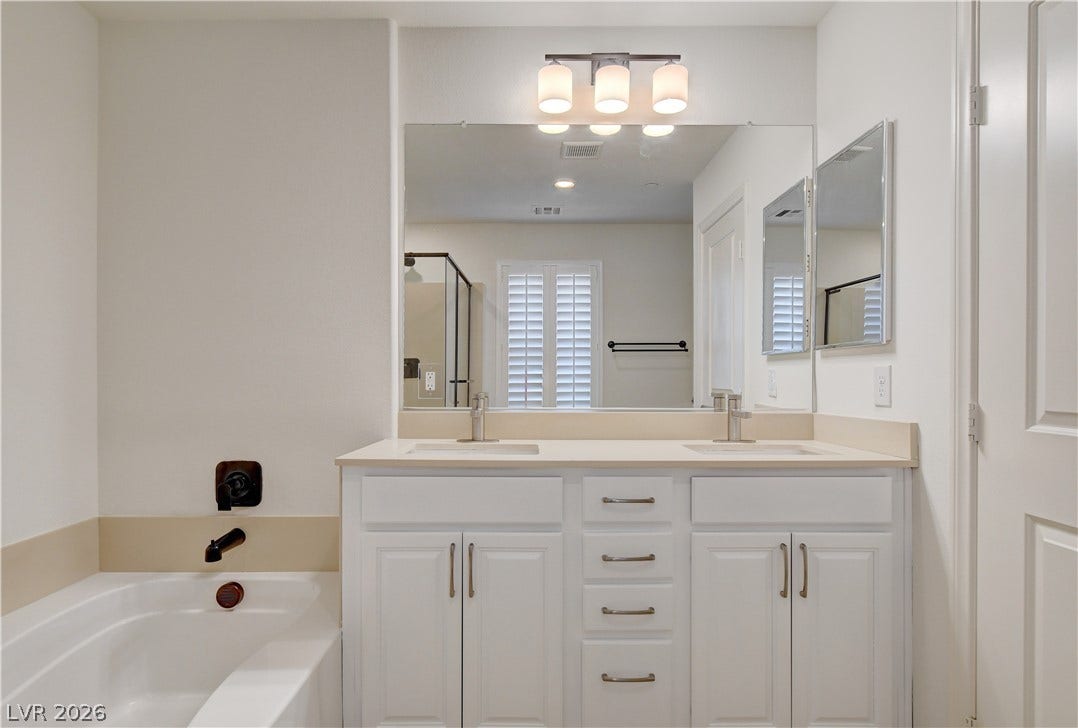A well-appointed primary bathroom features a dual vanity with ample storage and a built-in tub for relaxation.
