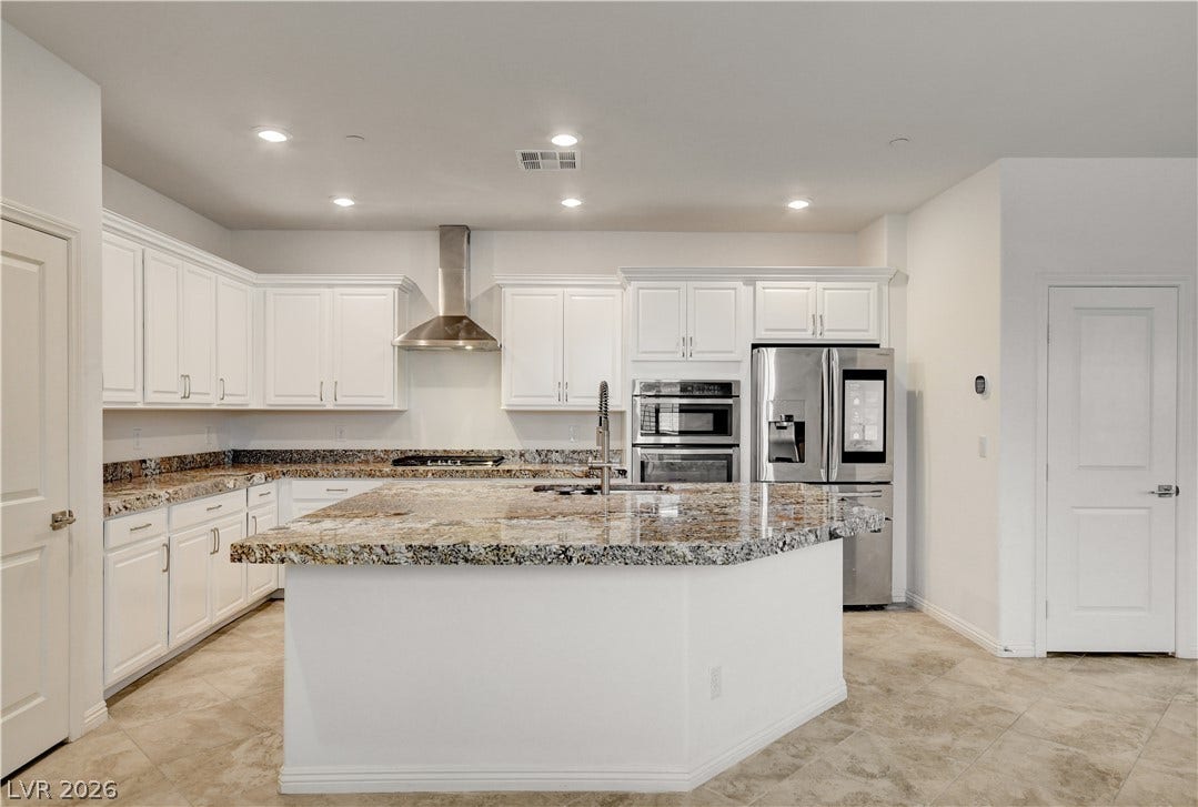 White cabinetry, granite counters, and stainless steel appliances create a sophisticated culinary space.