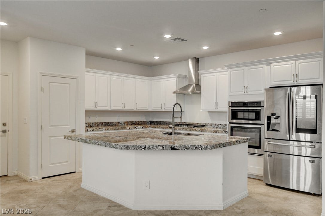 A contemporary kitchen showcases a large central island with a deep sink and an array of stainless steel appliances.
