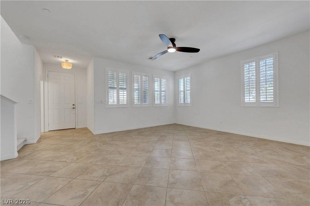 A tiled entryway leads into a naturally illuminated living area featuring shuttered windows and a modern ceiling fan.