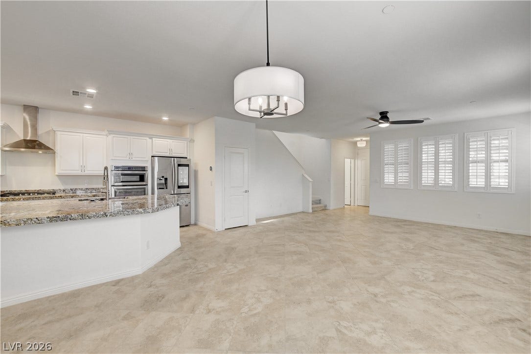 An open concept living space features a well-appointed kitchen with an island, flowing into a generous living area with tiled floors.