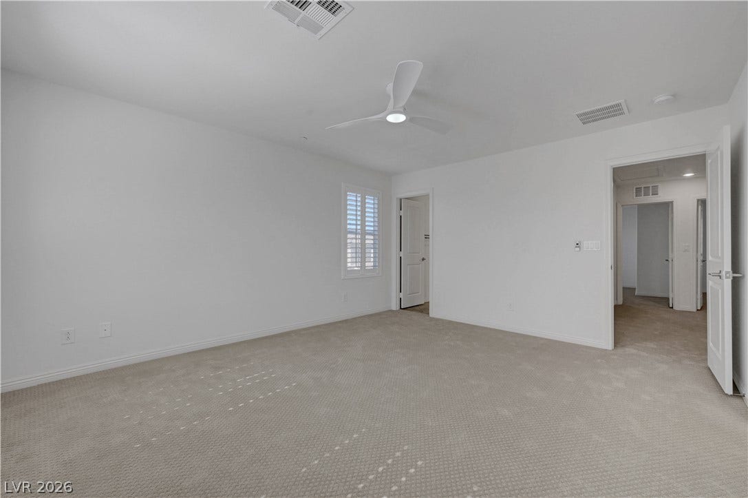A spacious bedroom awaits, featuring comfortable carpeting and a modern ceiling fan for year-round comfort.