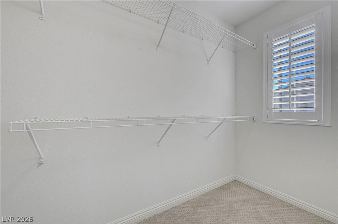 Functional wire shelving provides abundant storage space in this naturally illuminated walk-in closet.