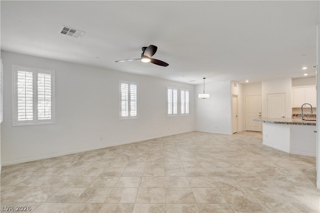 A spacious, airy room showcases durable tile flooring and abundant natural light filtering through window shutters.